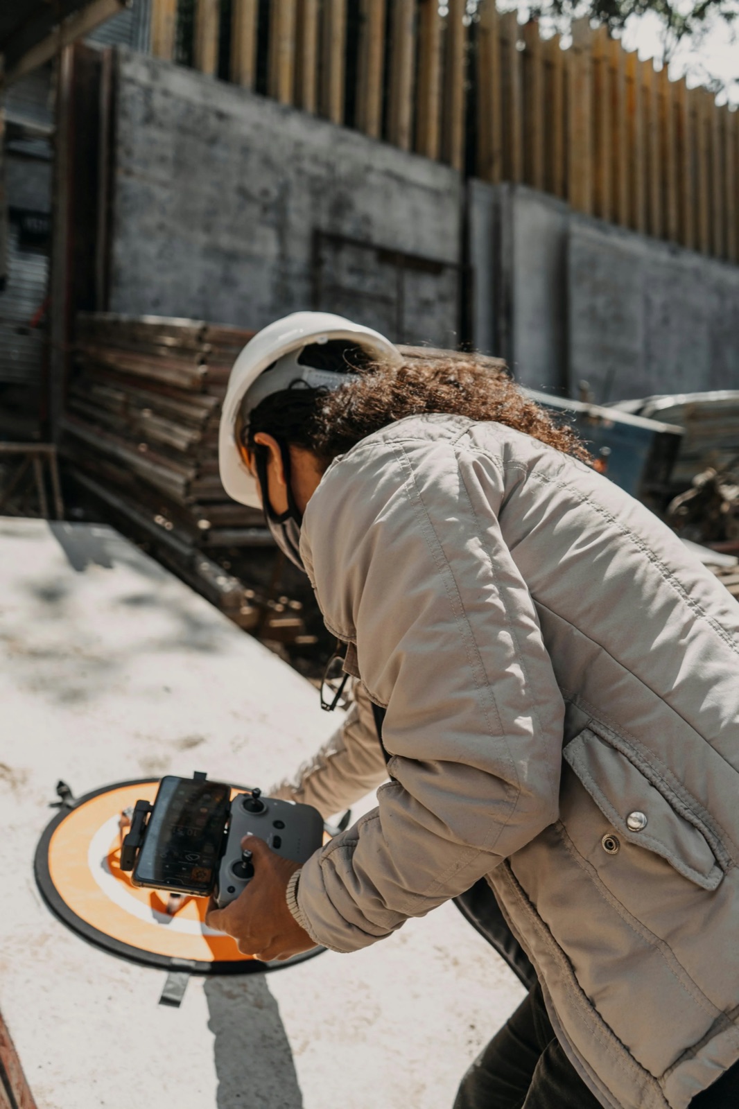 Pilot in a hard hat operating a drone controller outdoors
