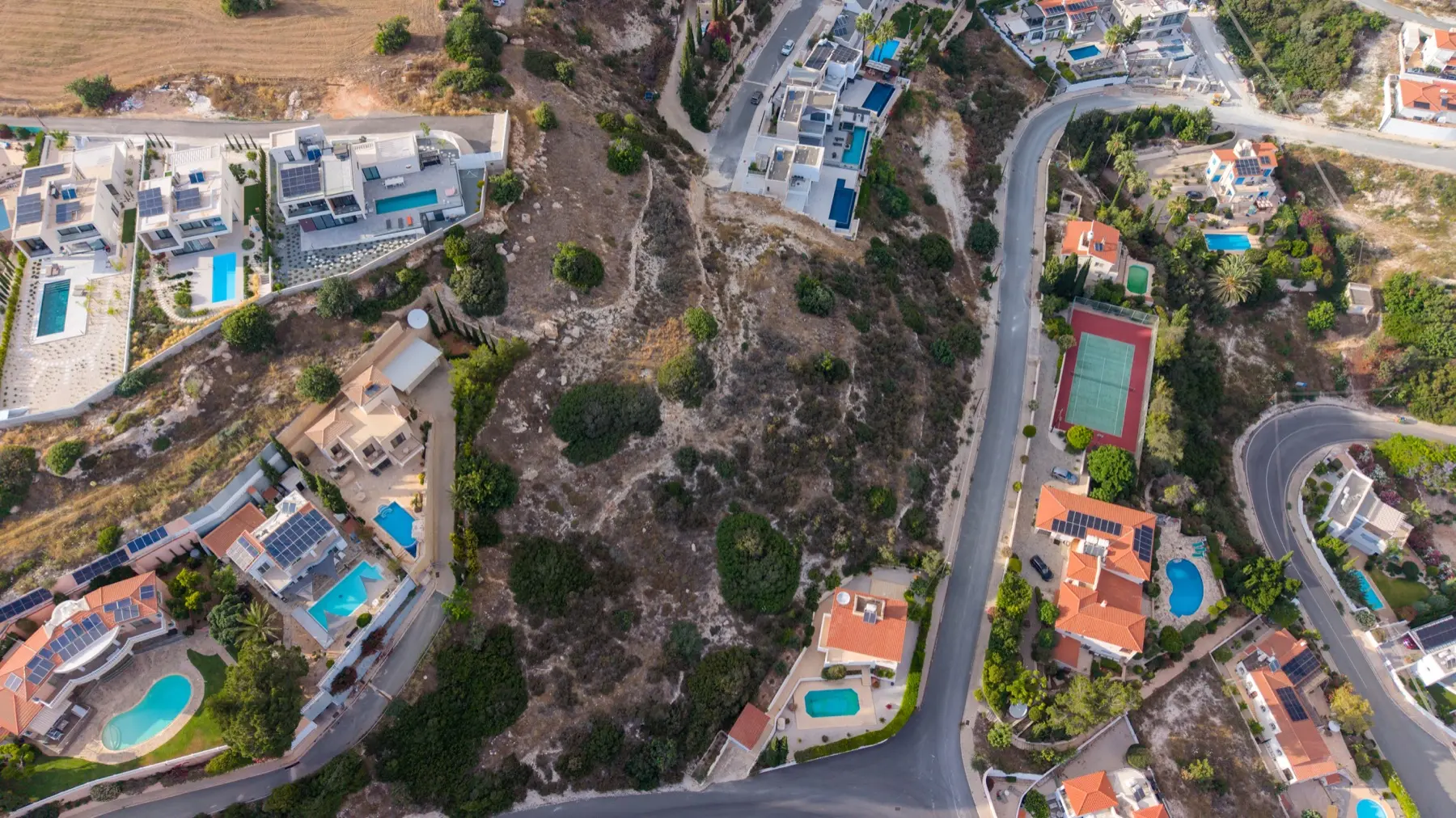 Aerial drone view of open plot land with roads and terrain from above