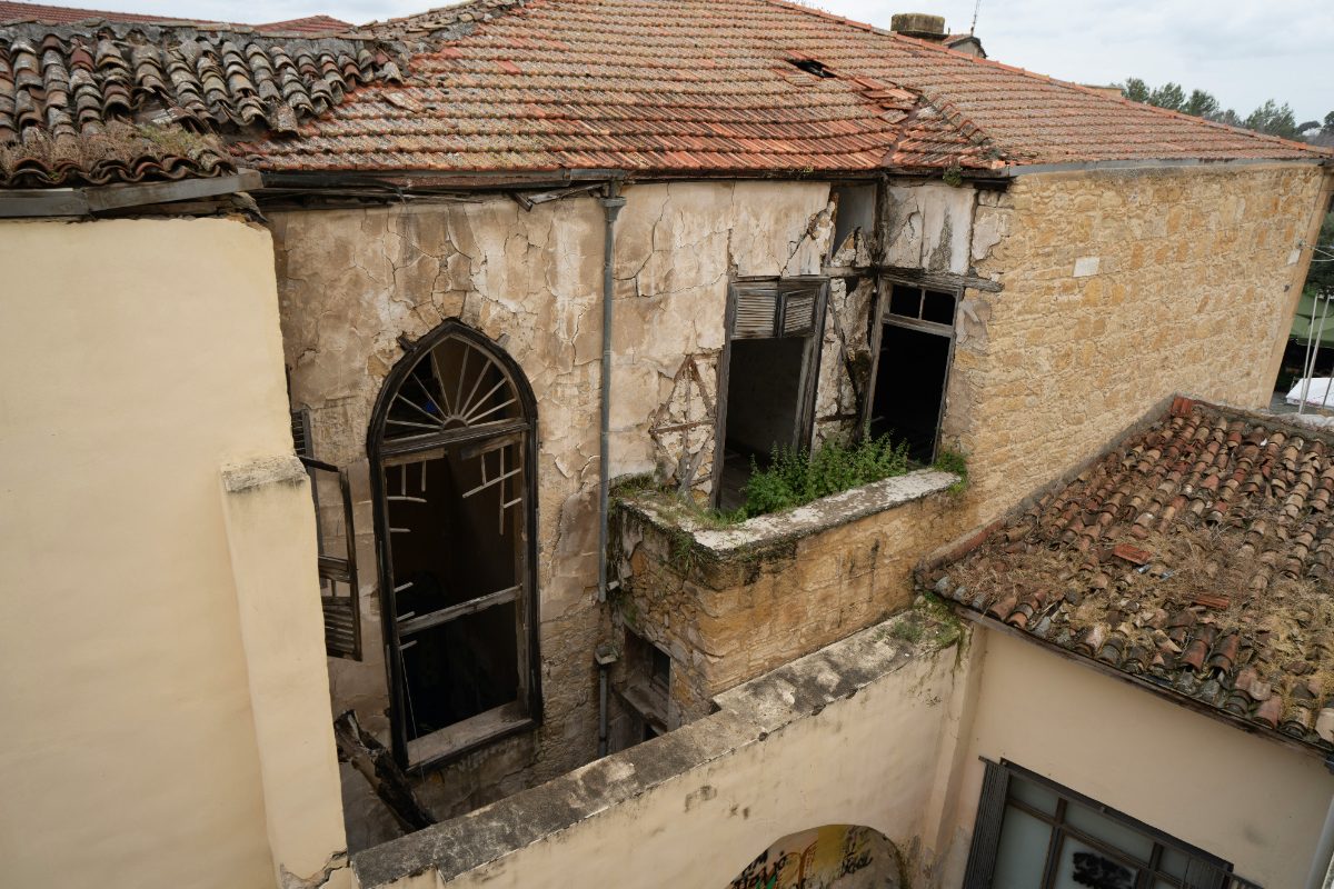 Close-range drone view of a cracked, damaged building facade and roofline